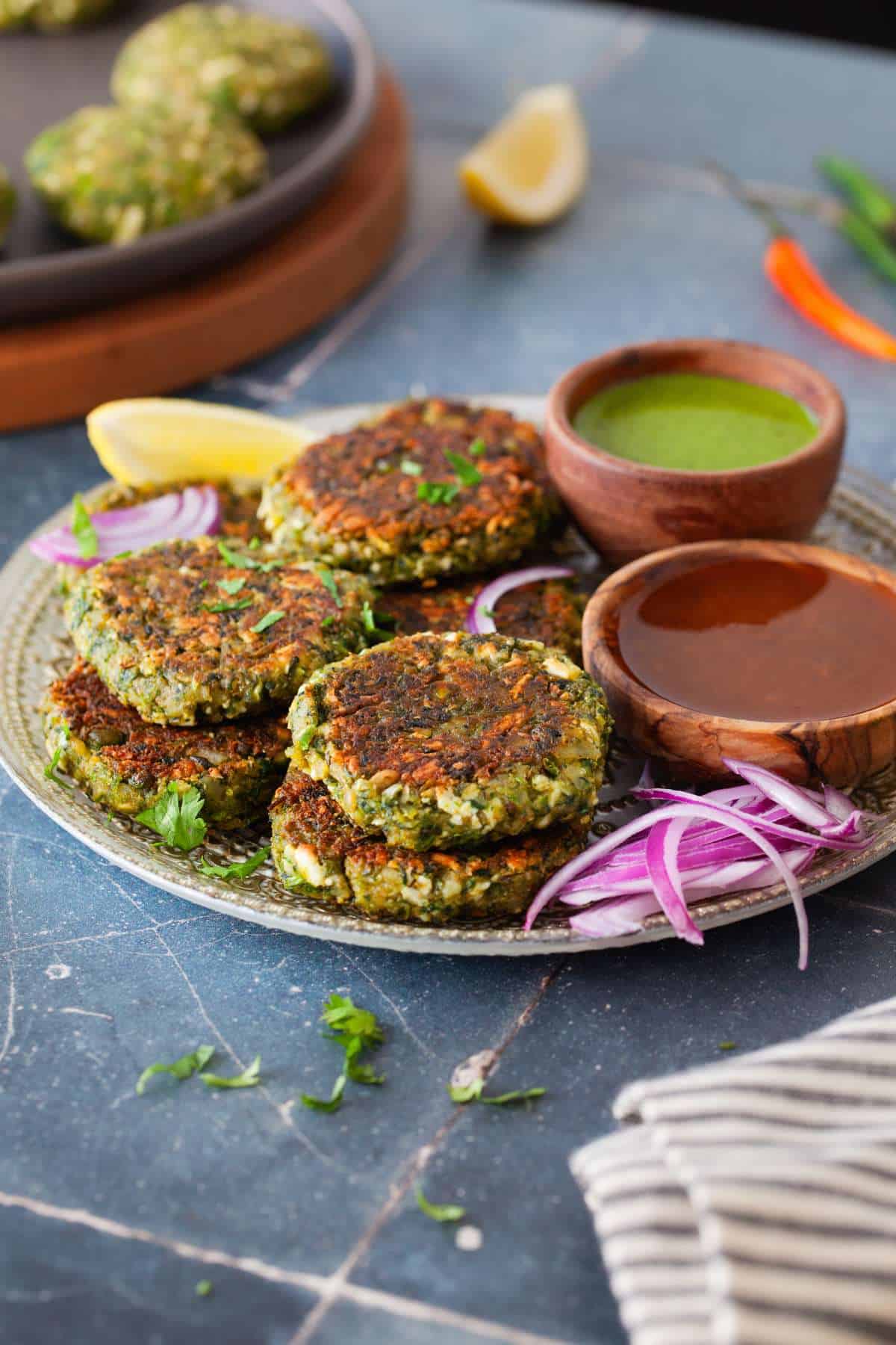 Side view of green kababs served with chutney.