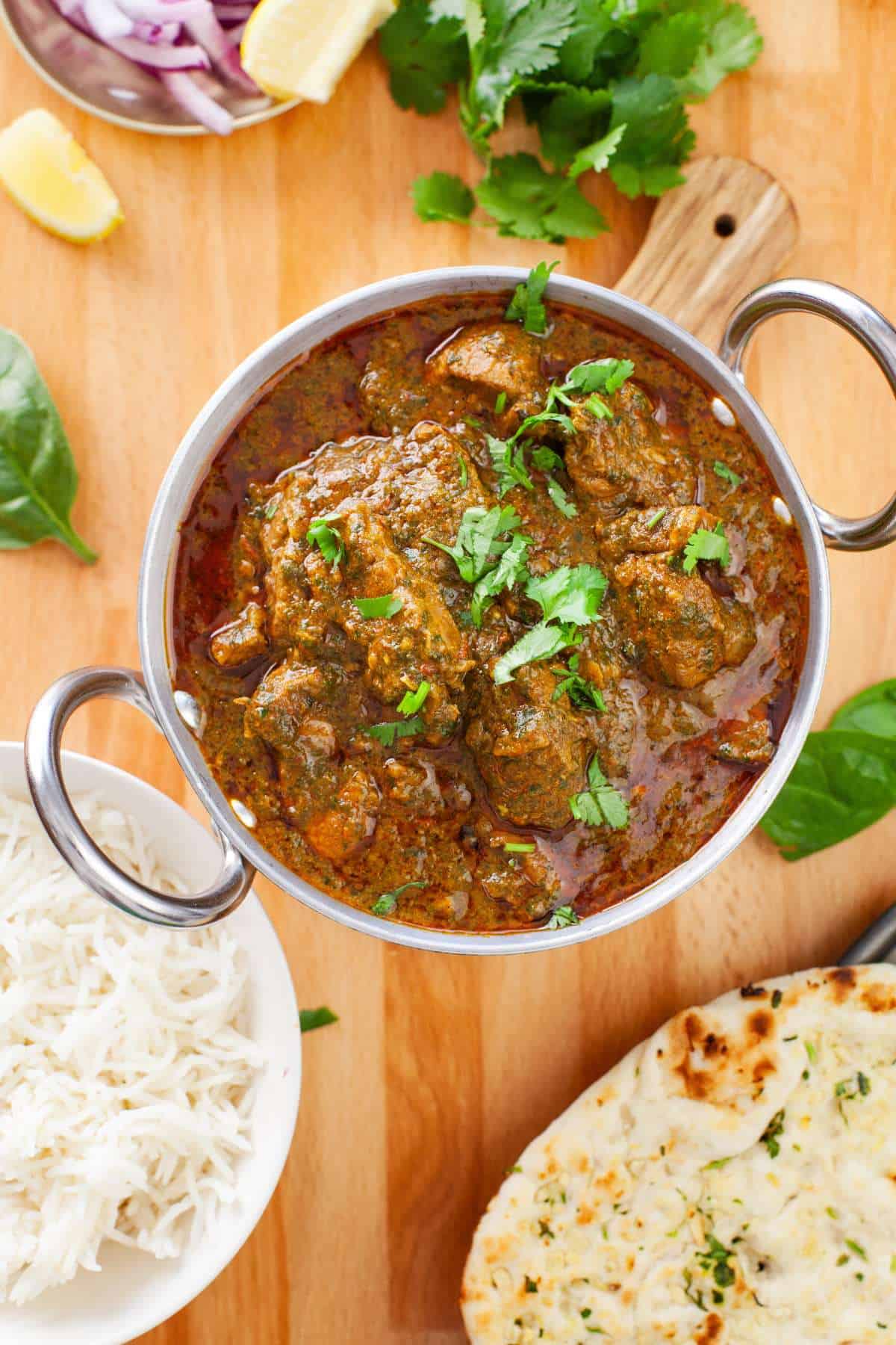 Lamb Saagwala served in an indian wok with rice and naan.
