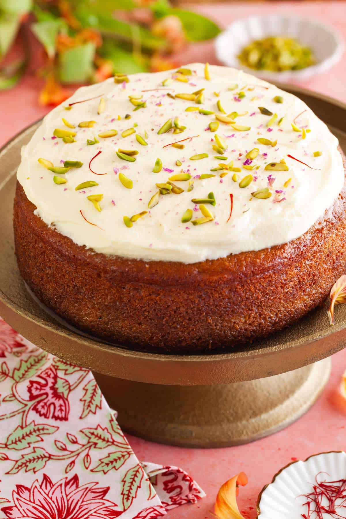 Mango flavored rasmalai cake served on a gold pedestal.