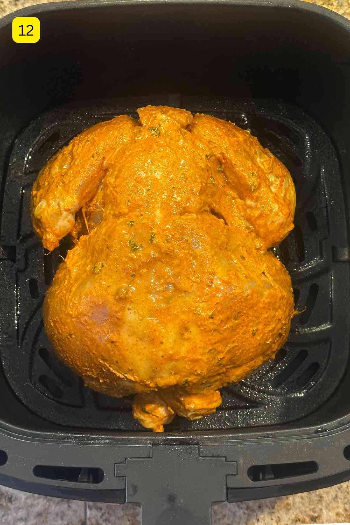 Whole tandoori chicken placed in an air fryer basket.