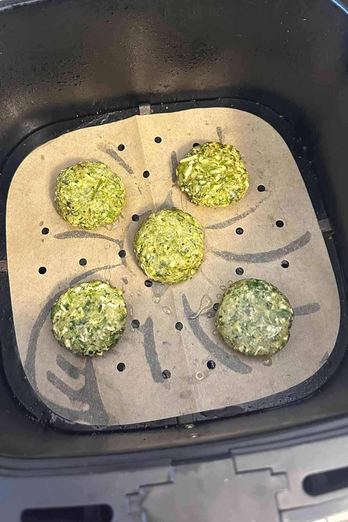 Green kabab placed in air fryer basket.