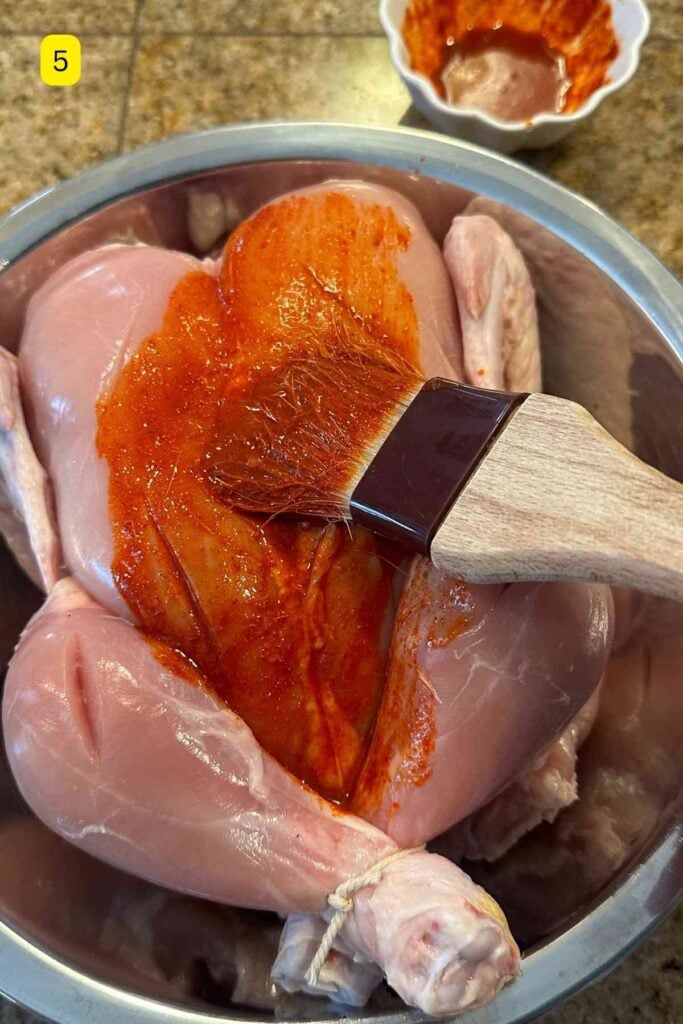 Brushing first marinade over whole chicken.