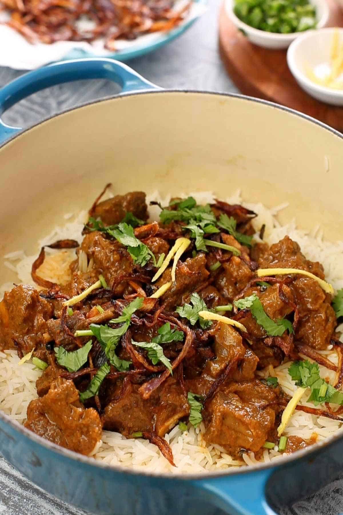 Layering biryani in a large blue dutch oven.