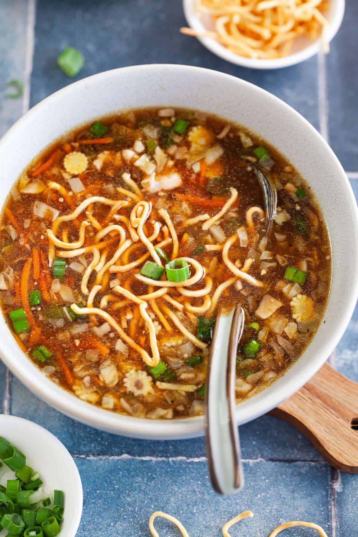 Closeup image of chicken manchow soup garnished with crispy noodles.