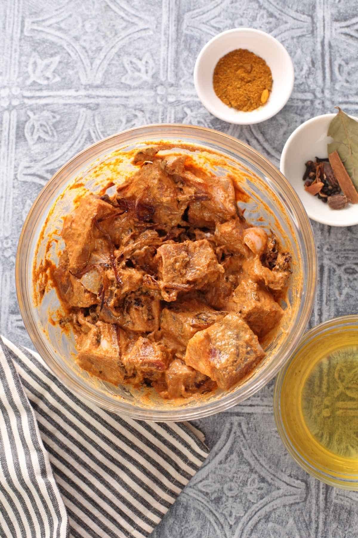 Marinated mutton meat in a alrge glass bowl.