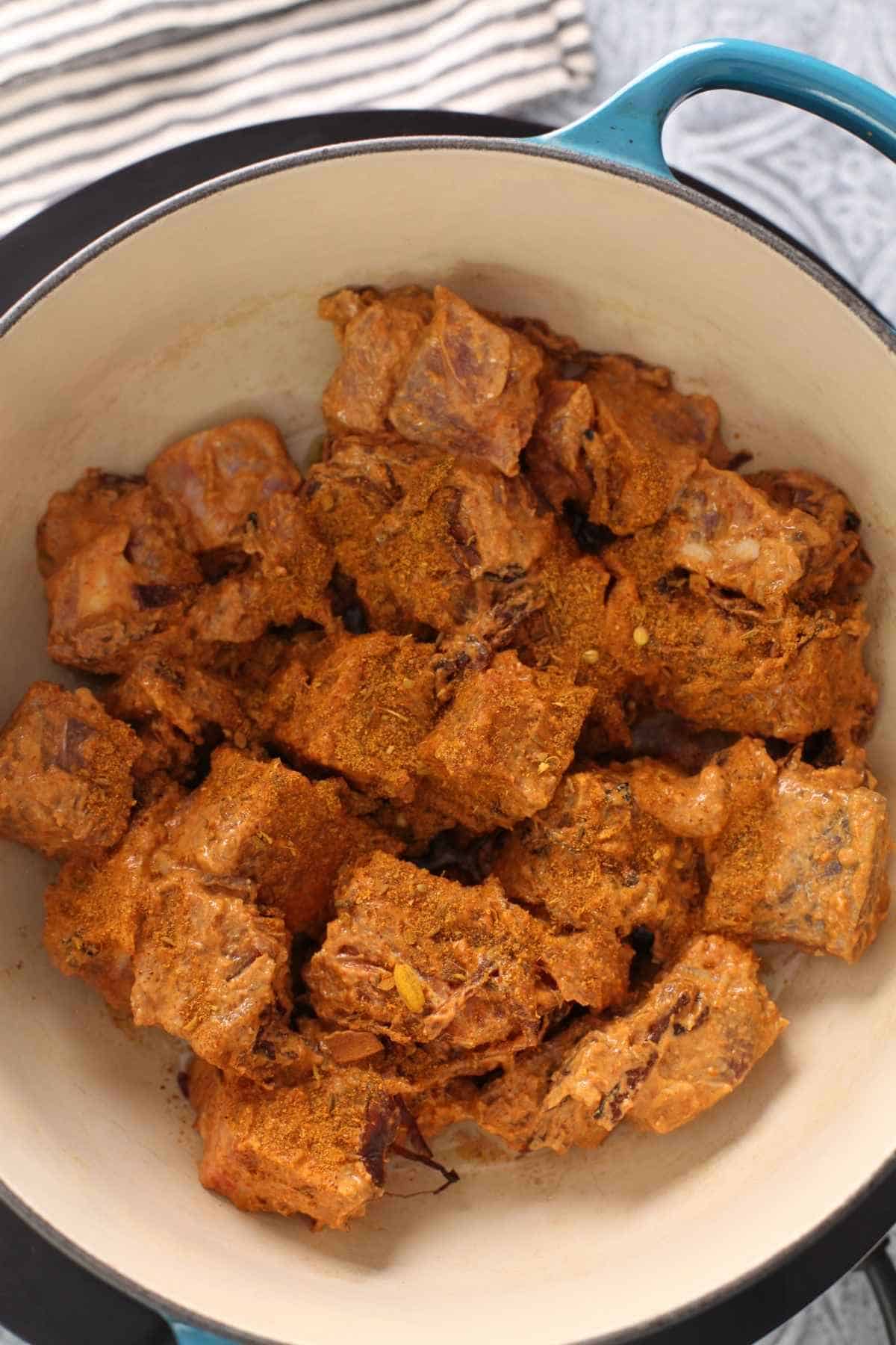 Marinated mutton added to oil and sprinkled with biryani masala.