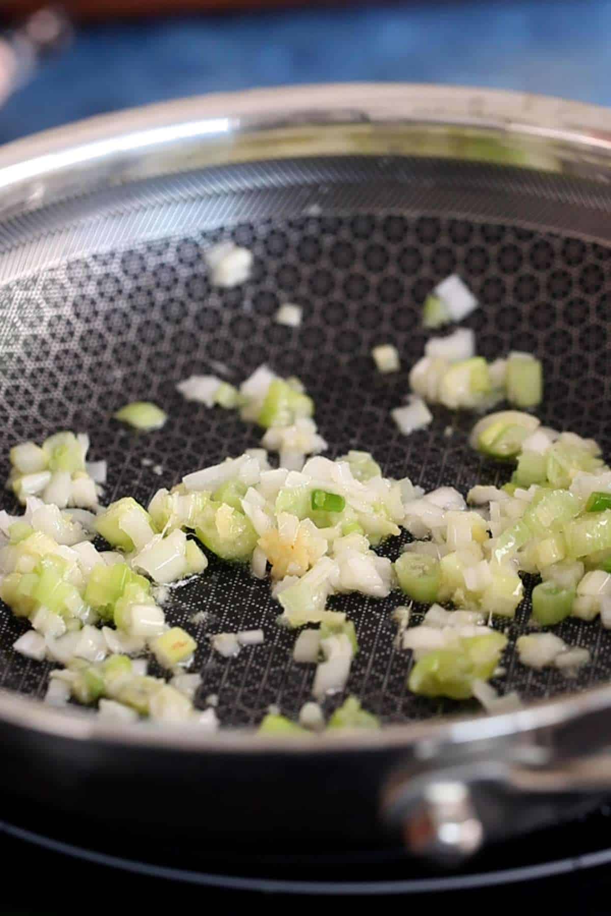Sauteed scallions and garlic in ablack non stick pan.