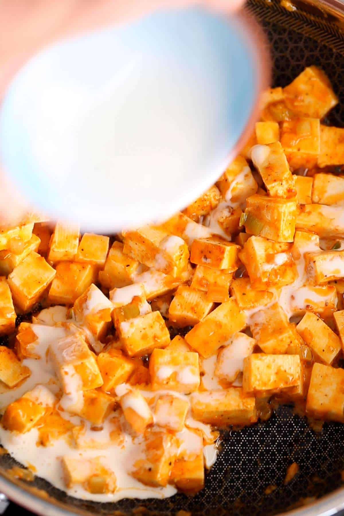 Adding heavy cream to paneer.