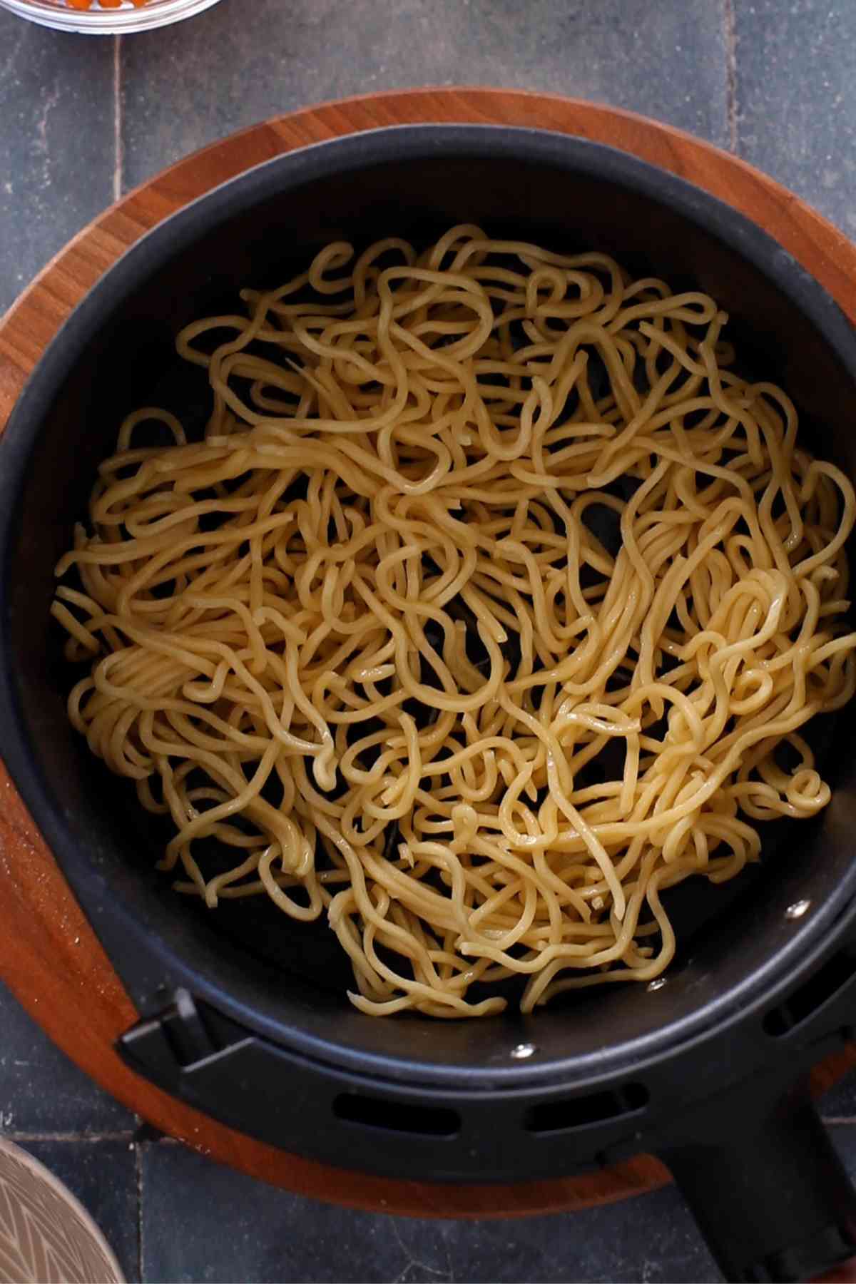 Noodles in an air fryer basket.