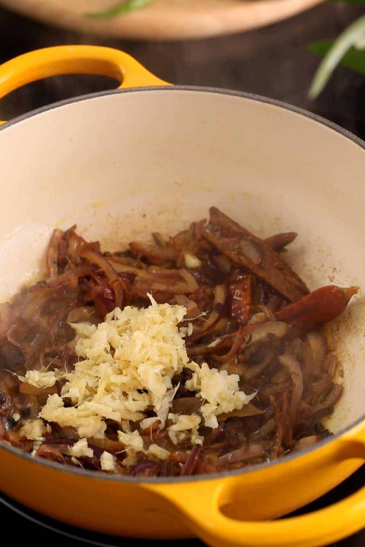 Adding minced ginger and garlic to the onions. 