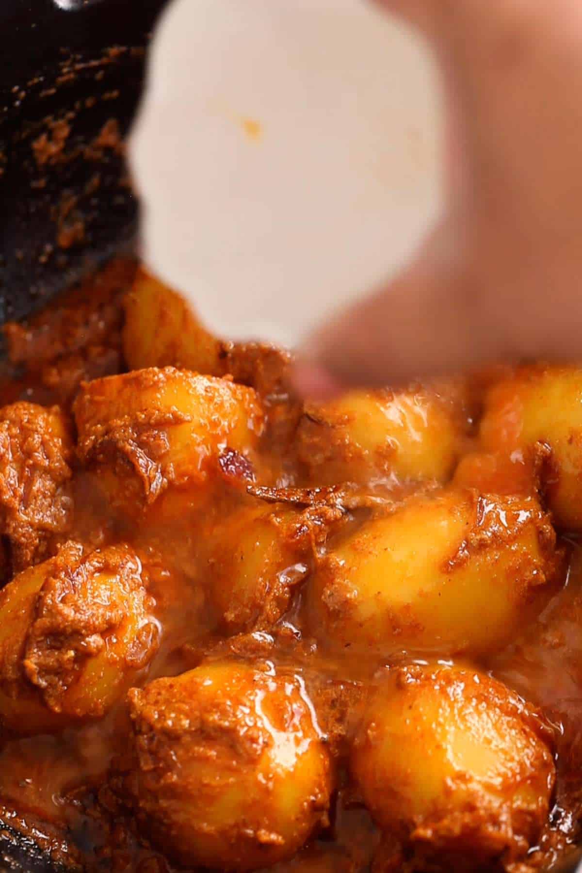 Adding water to dum aloo.