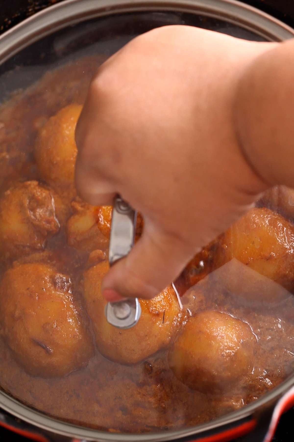 Covering the cooking pot with lid to let potatoes dum cook.