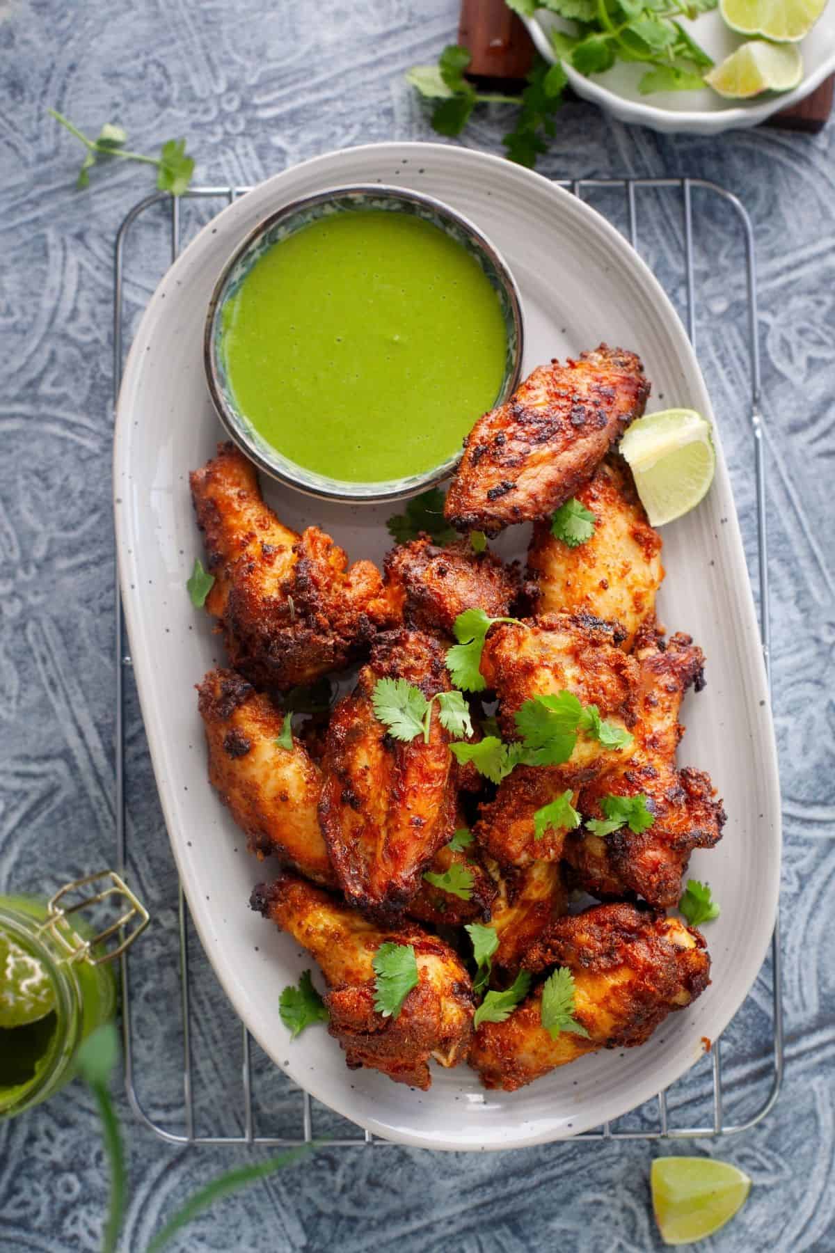 Air fryer curry chicken wings served on a grey platter with green chutney.