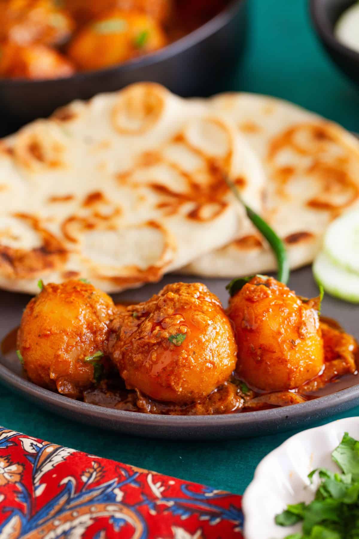 Aloo dum served with naan on a plate.