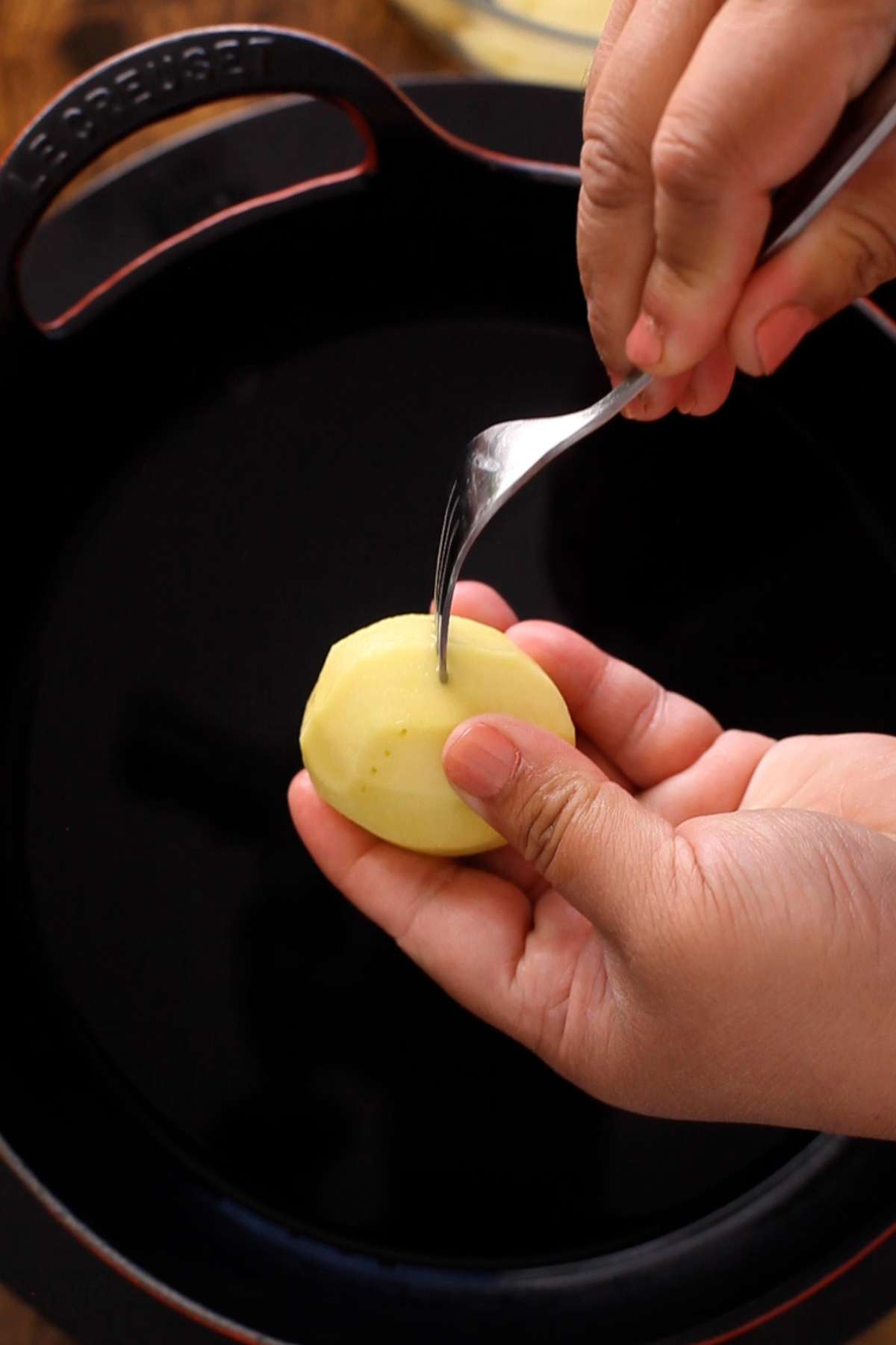 Poking baby potatoes with fork.