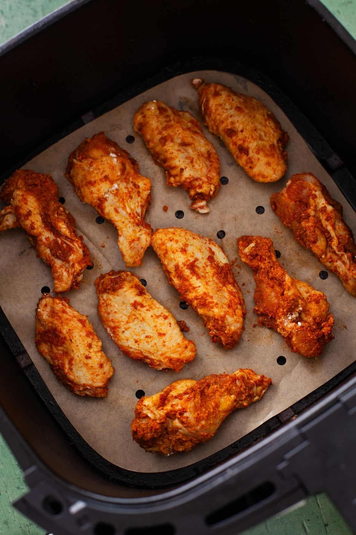 Chicken wings placed in a single layer in the airf fryer basket.