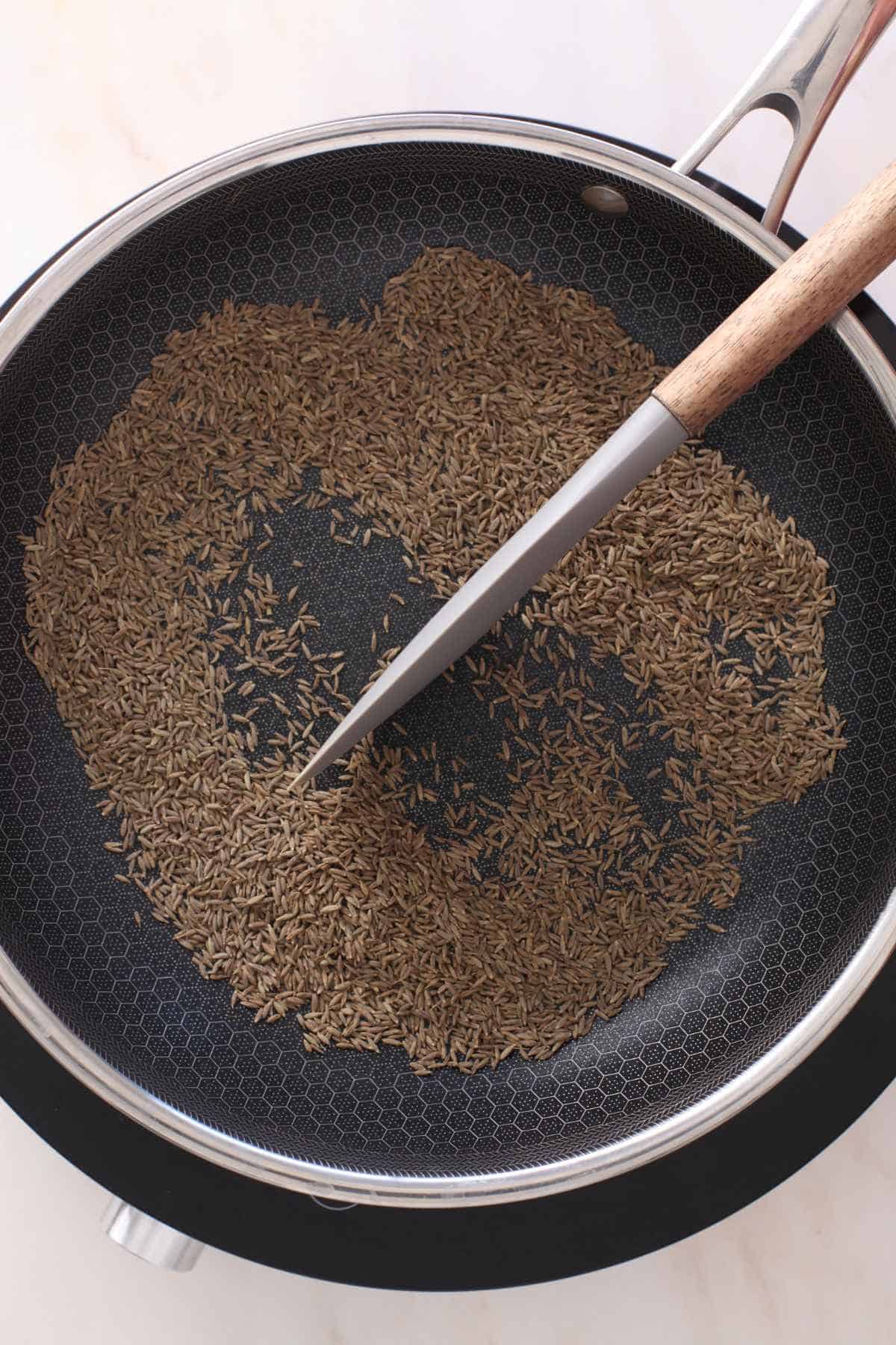 Continously stirring the cumin seeds.