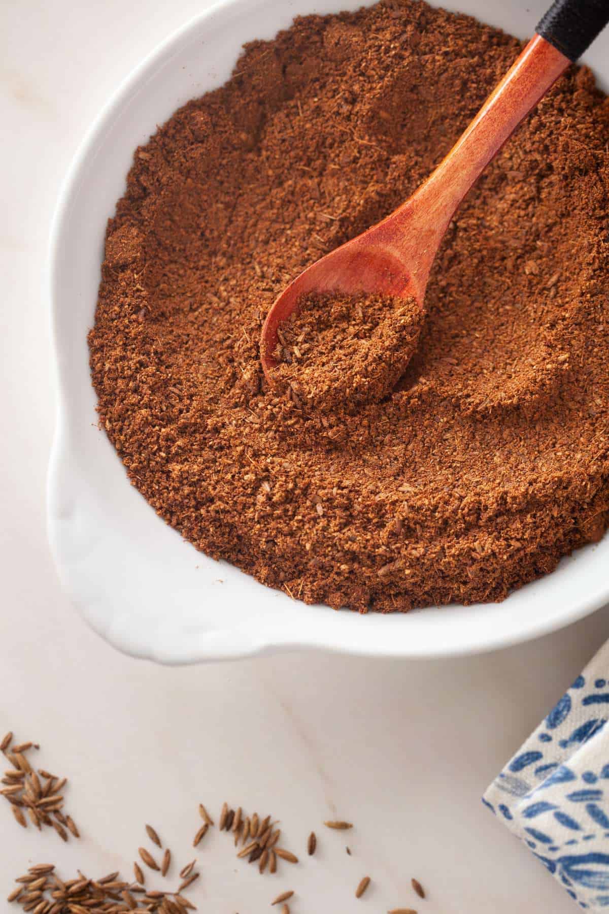 Close up of roasted cumin powder in a white bowl. 