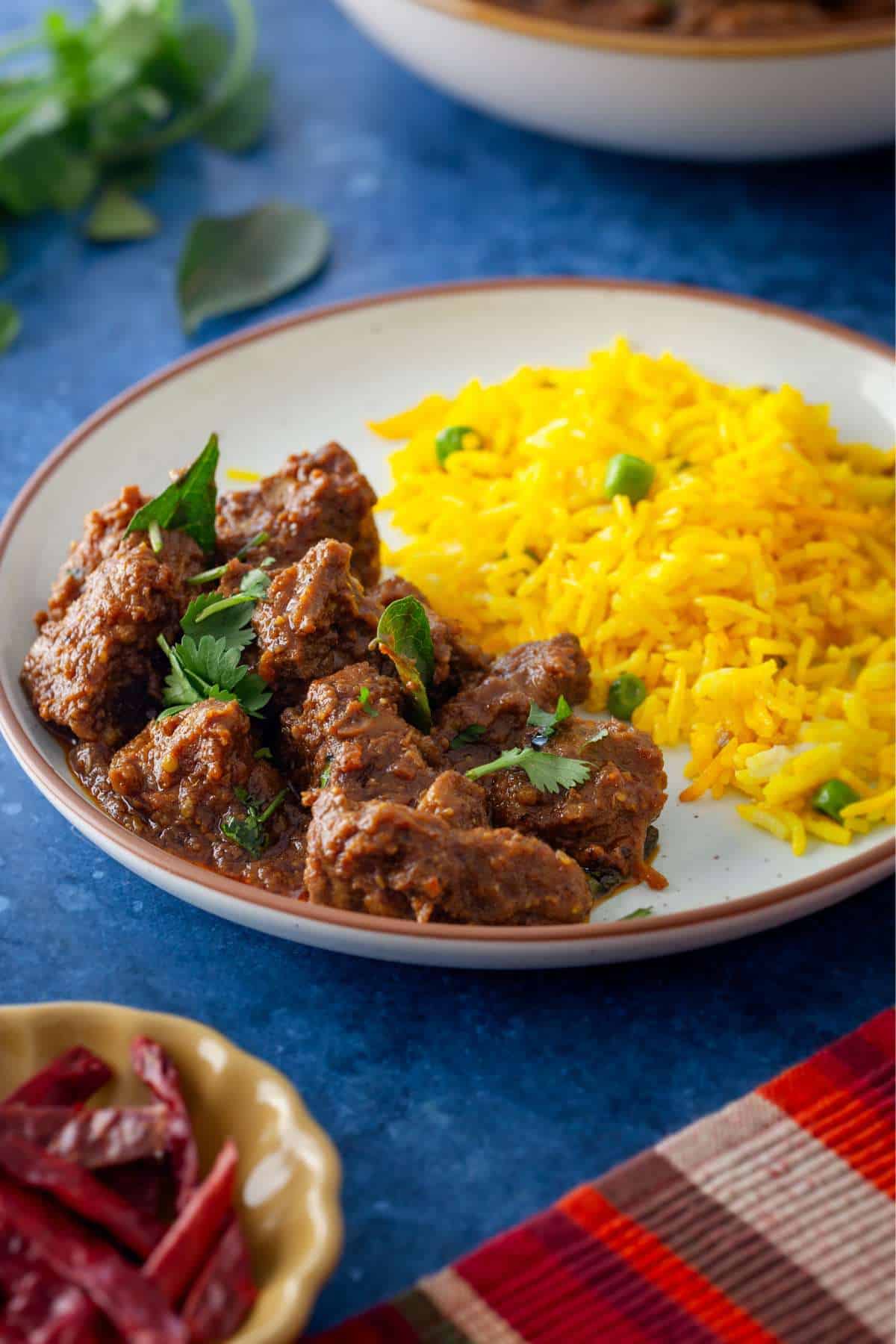 Lamb Madras served with turmeric rice in a white plate.