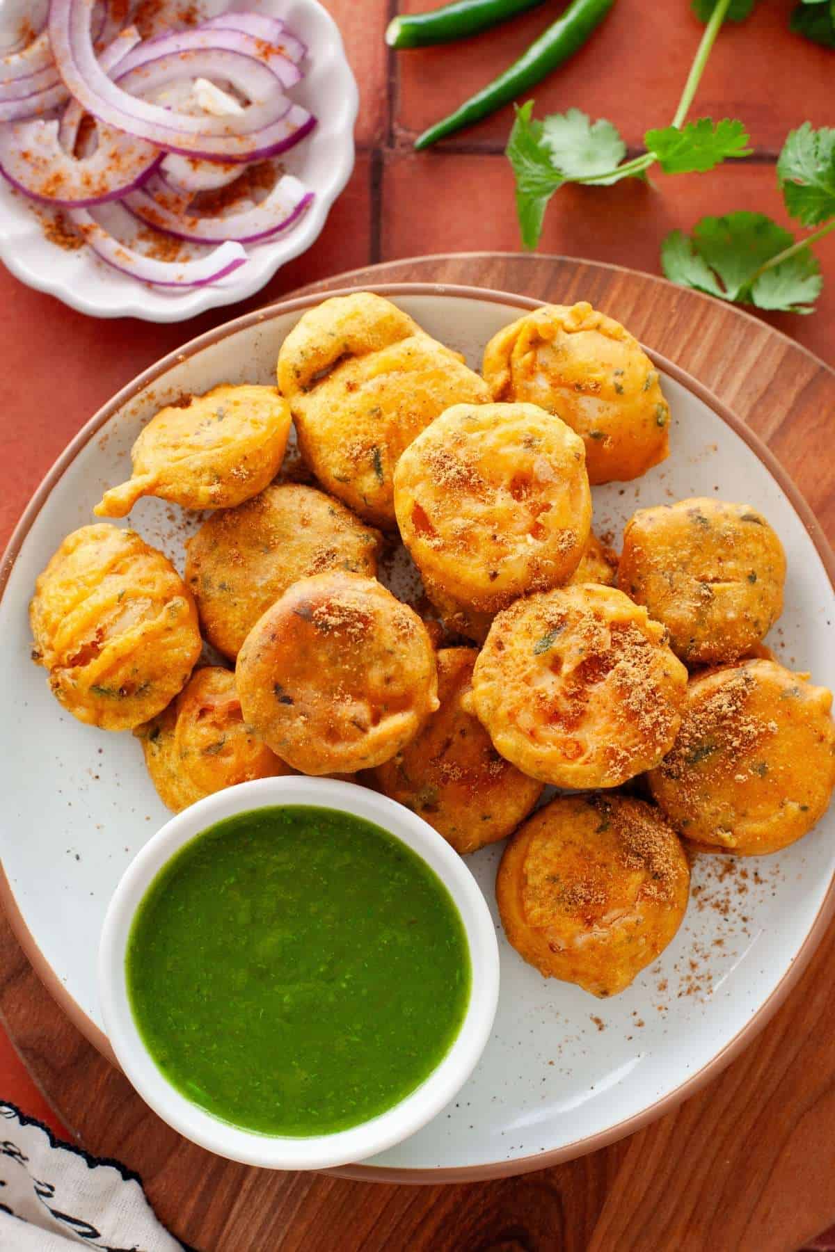 Egg bonda served with green chutney and onion slices.