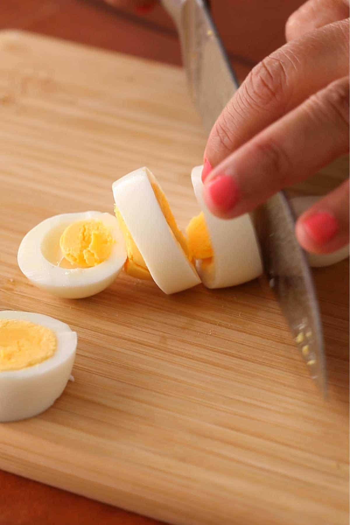 Slicing hard boiled eggs on a bambo cutting board. 