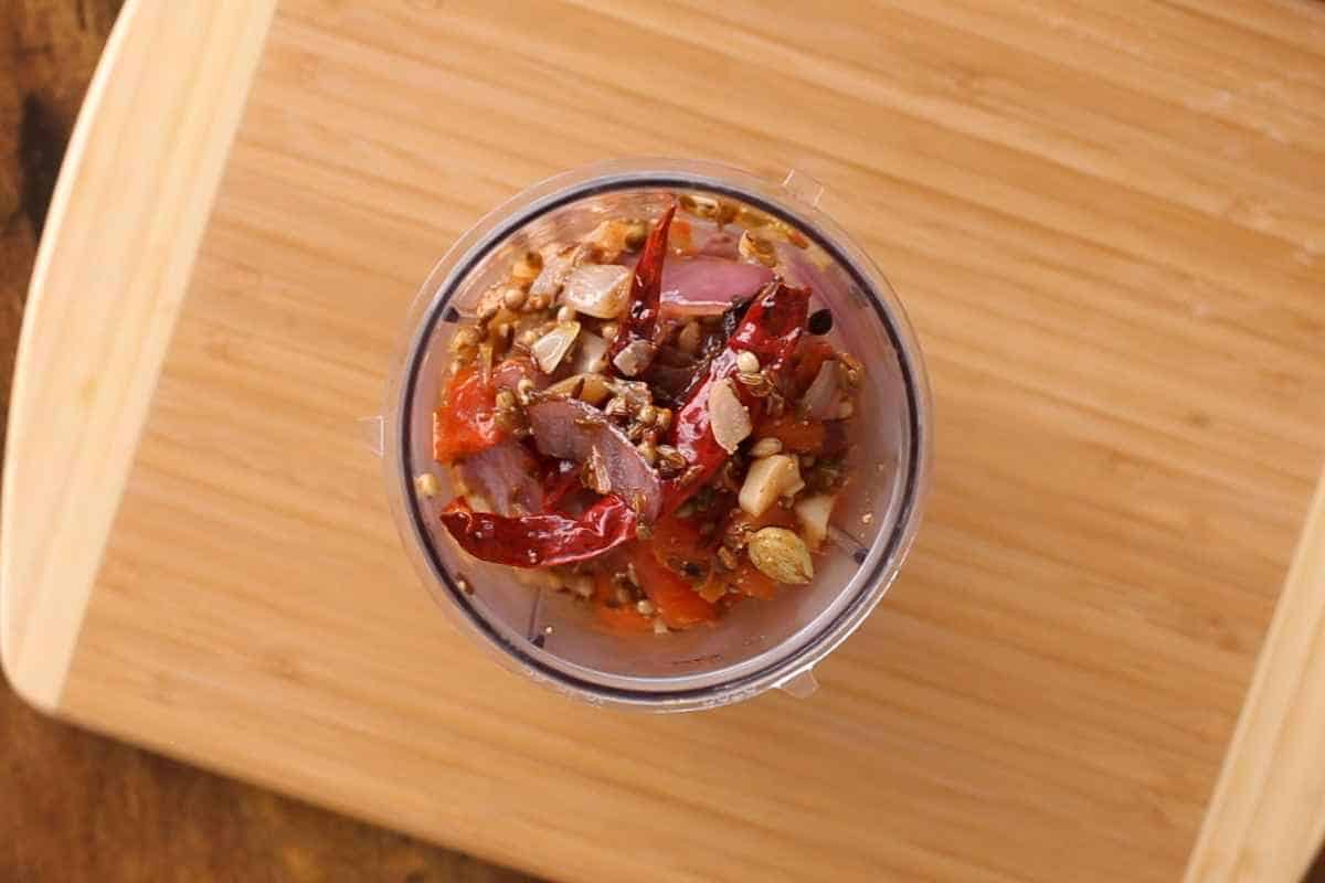 Tomatoes, onions and whole spcies in a blender jar.