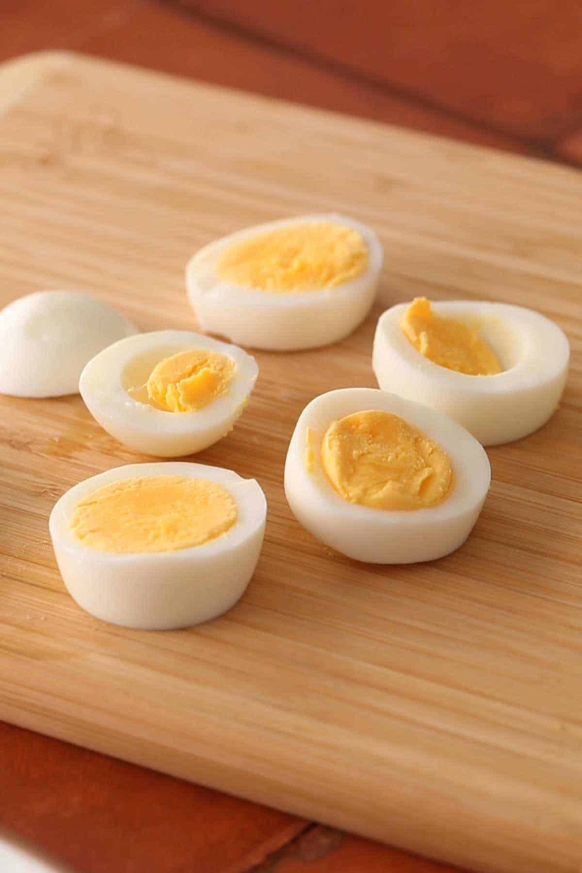 Hard boiled egg slices on a bamboo cutting board.