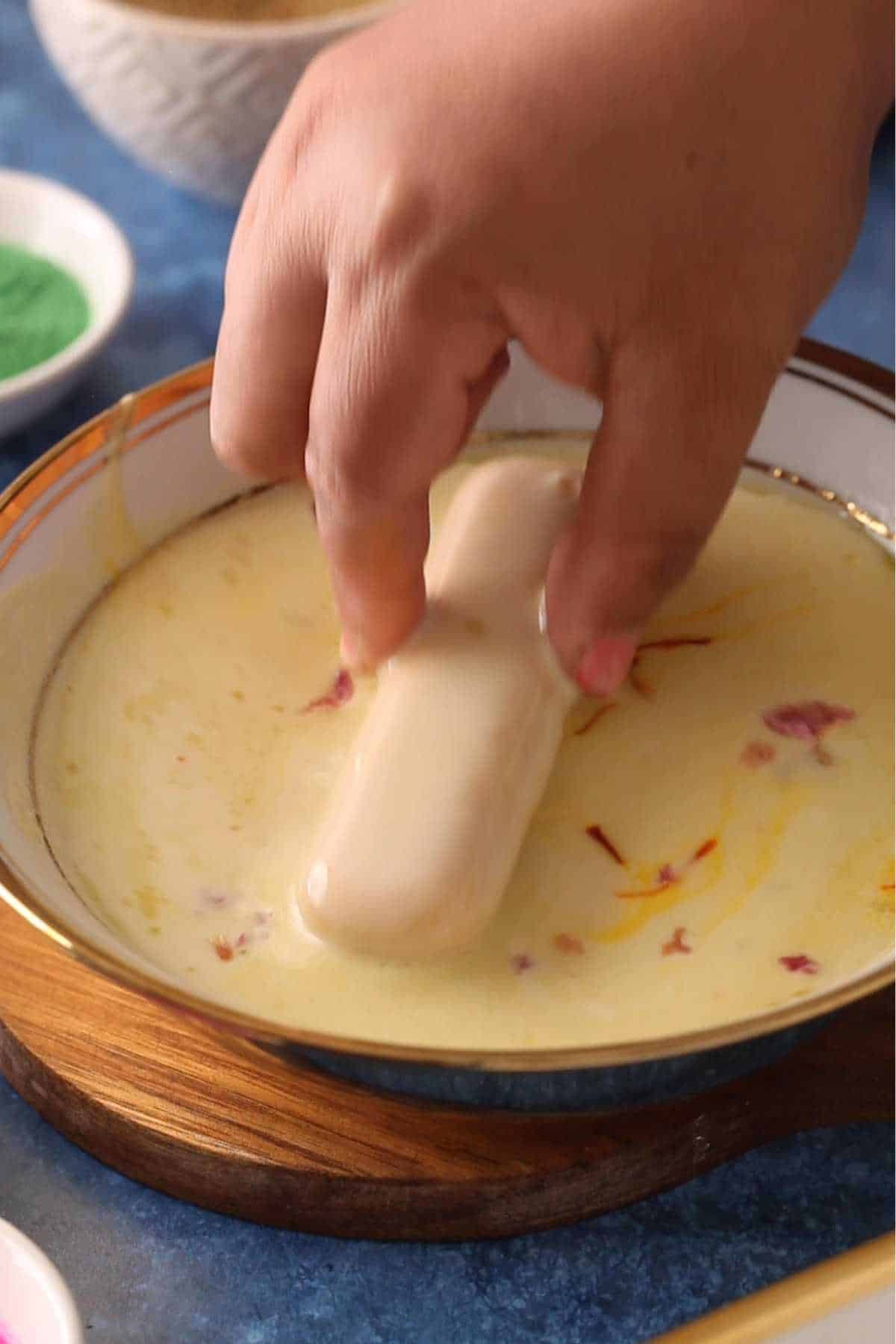 Dipping lady finger cookies in thandai.