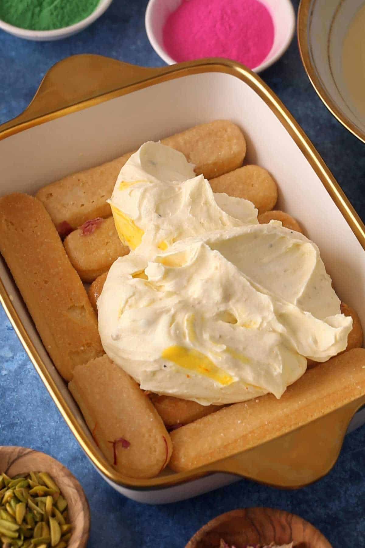 Topping laydfingers with thandai masala whipped cream.