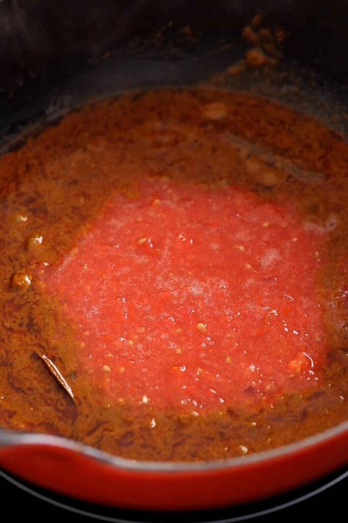 Crushed tomatoes are added to the browned onion and spices.