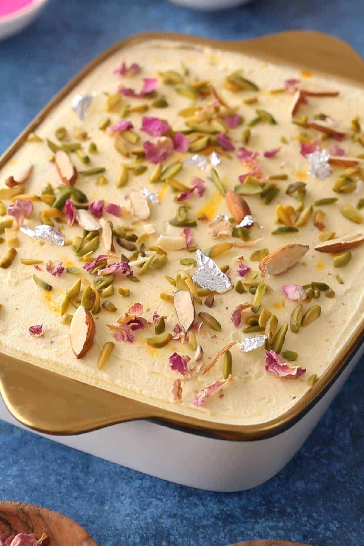 Thandai tiramisu decoraded with nuts, rose petals and silver leaf.