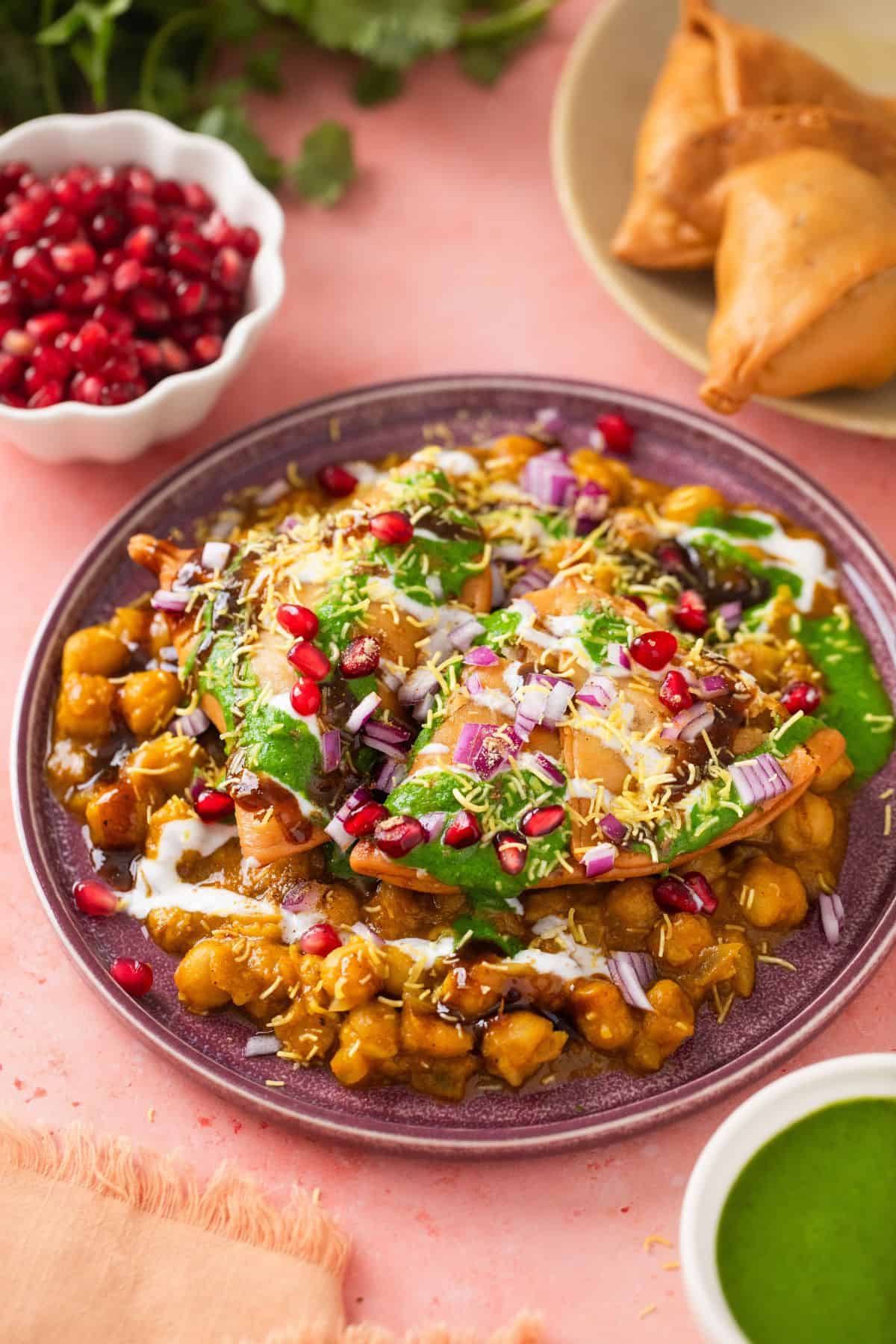 Side view of samosa chaat with fried samosa in background.