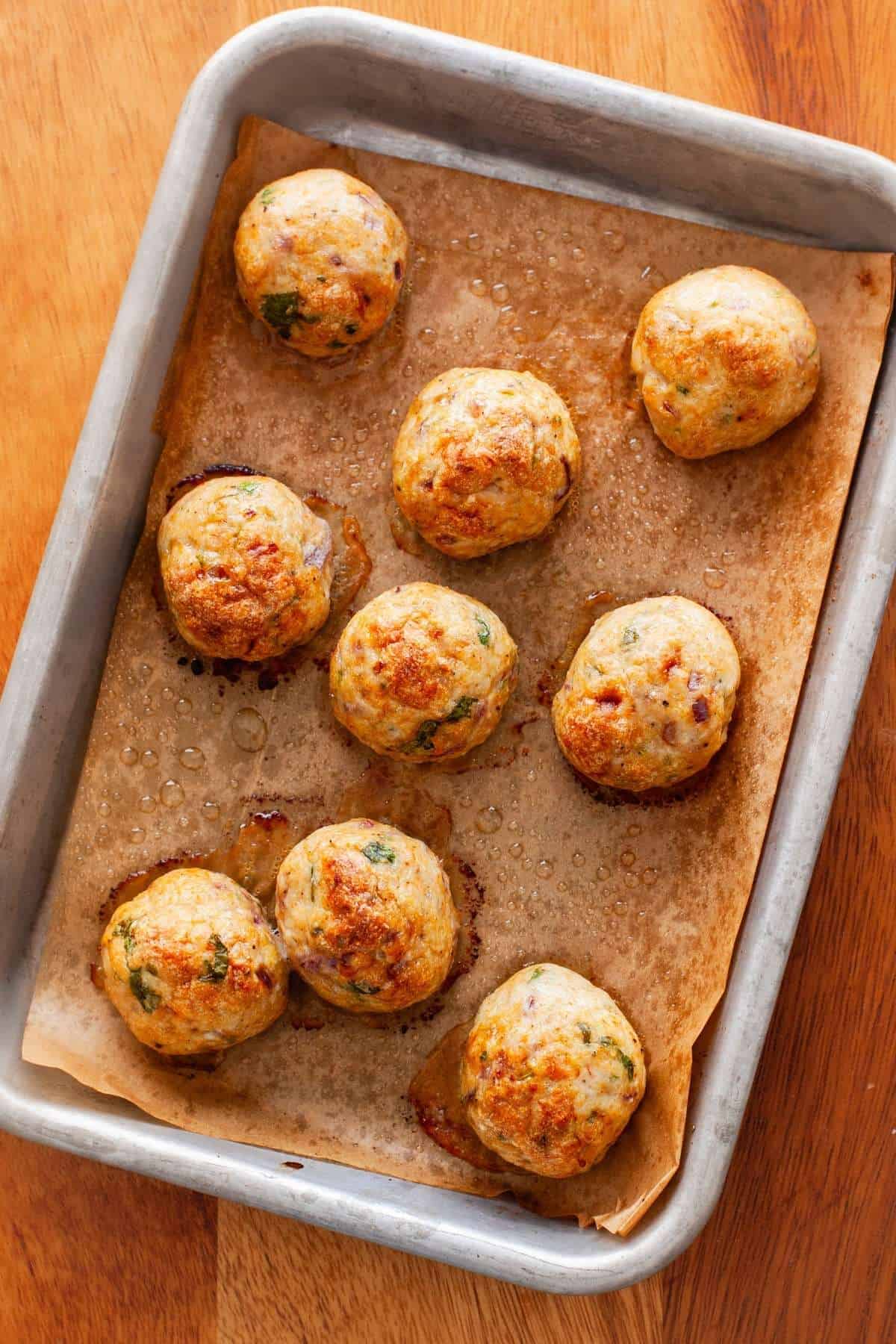 Baked chicken kofta meatballs on a baking sheet.