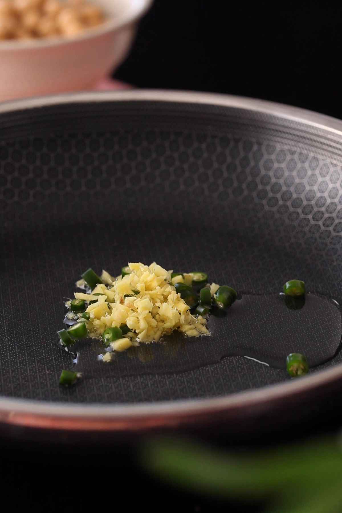 Chopped ginger and green chillies sizzing in hot oil.