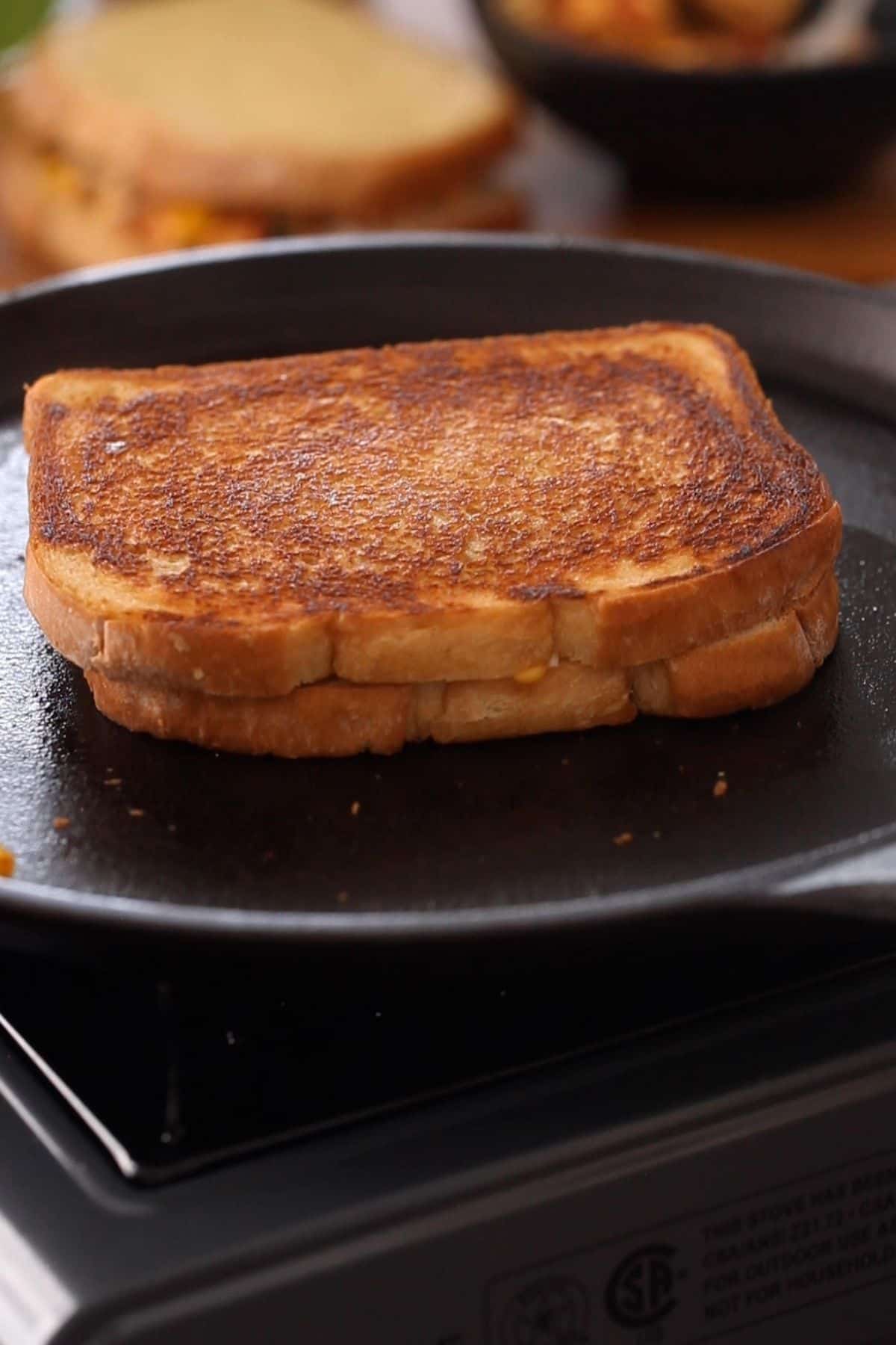Paneer sandwich toasted to golden brown on a cast iron griddle.