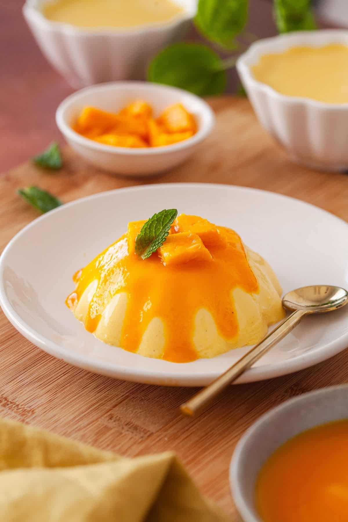 Close up of panna cotta on a dessert plate with a gold spoon.