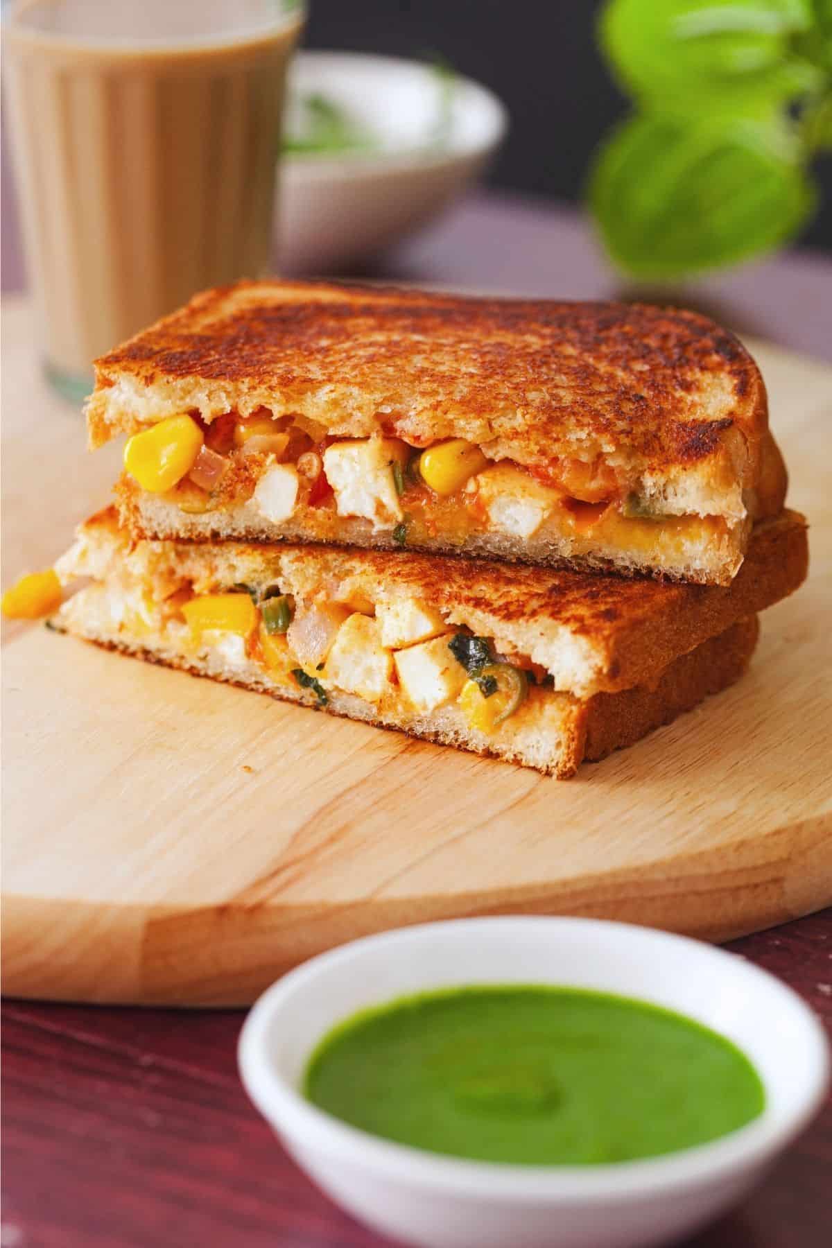 Paneer Sanwich stacked on each other and served with cilantro chutney and masala chai.