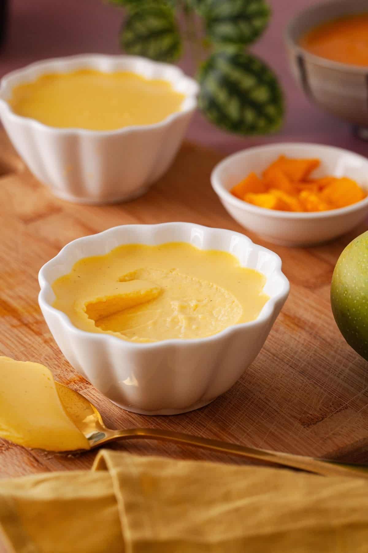 Mango panna cotta is scooped in the centre to show its delicate texture.