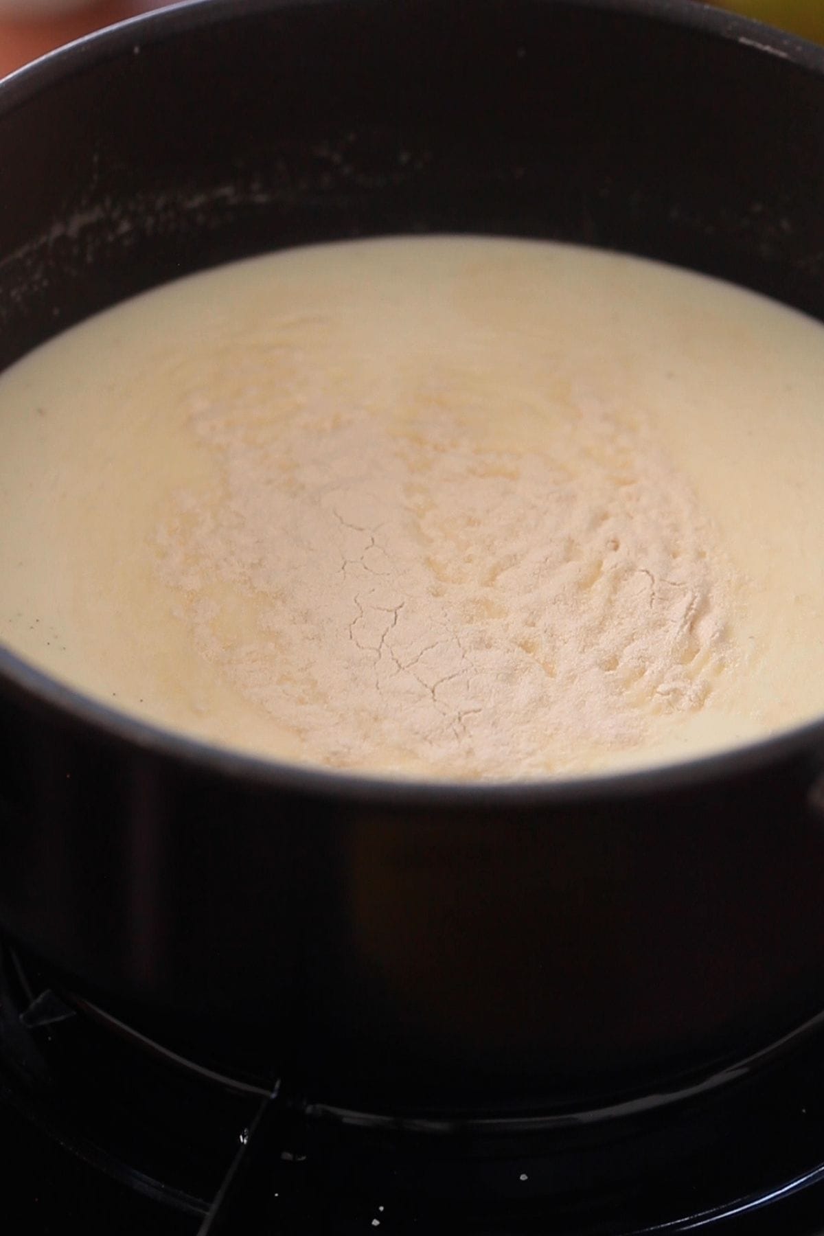 Panna Cotta ingredients added to a black saucepan.