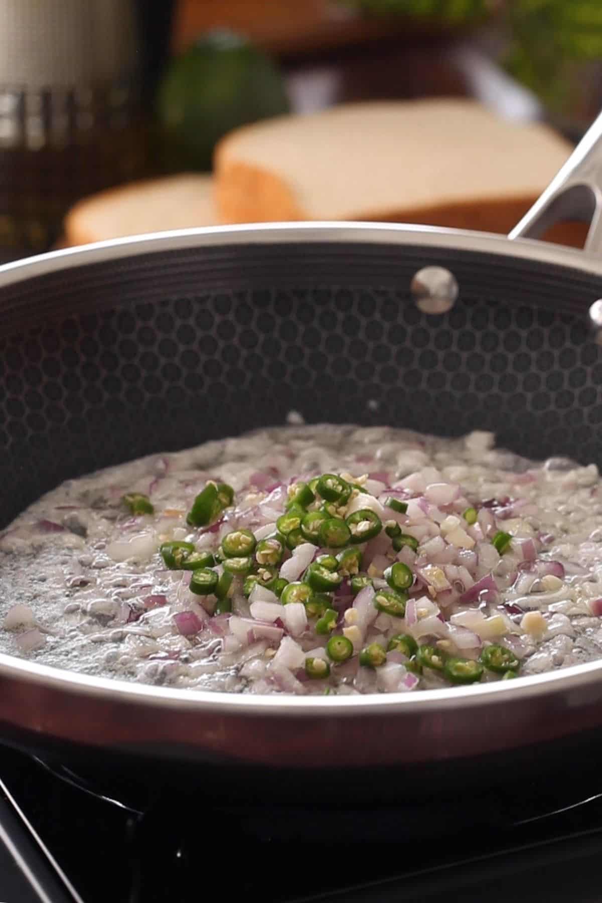 Frying chopped onions and green chilies in butter.