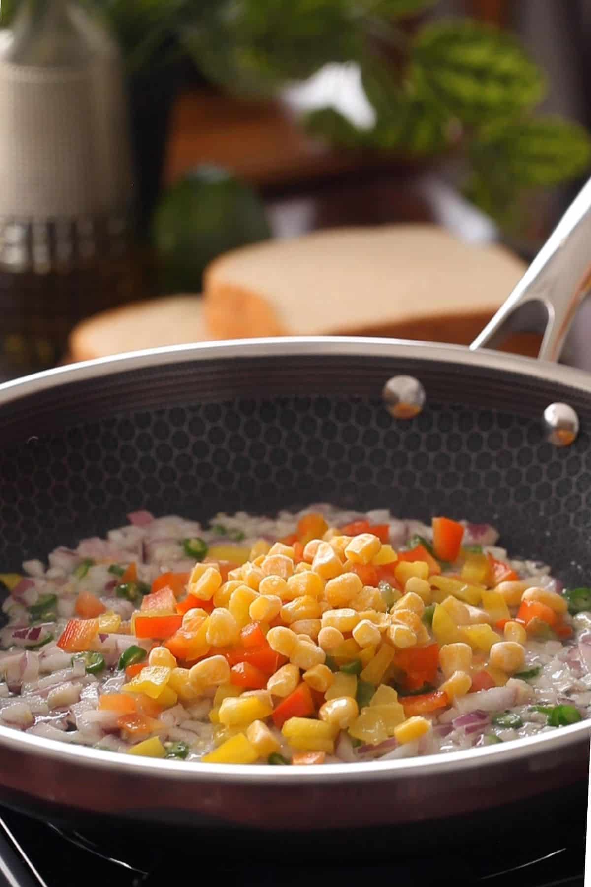 Adding colorful vegetables to the skillet.