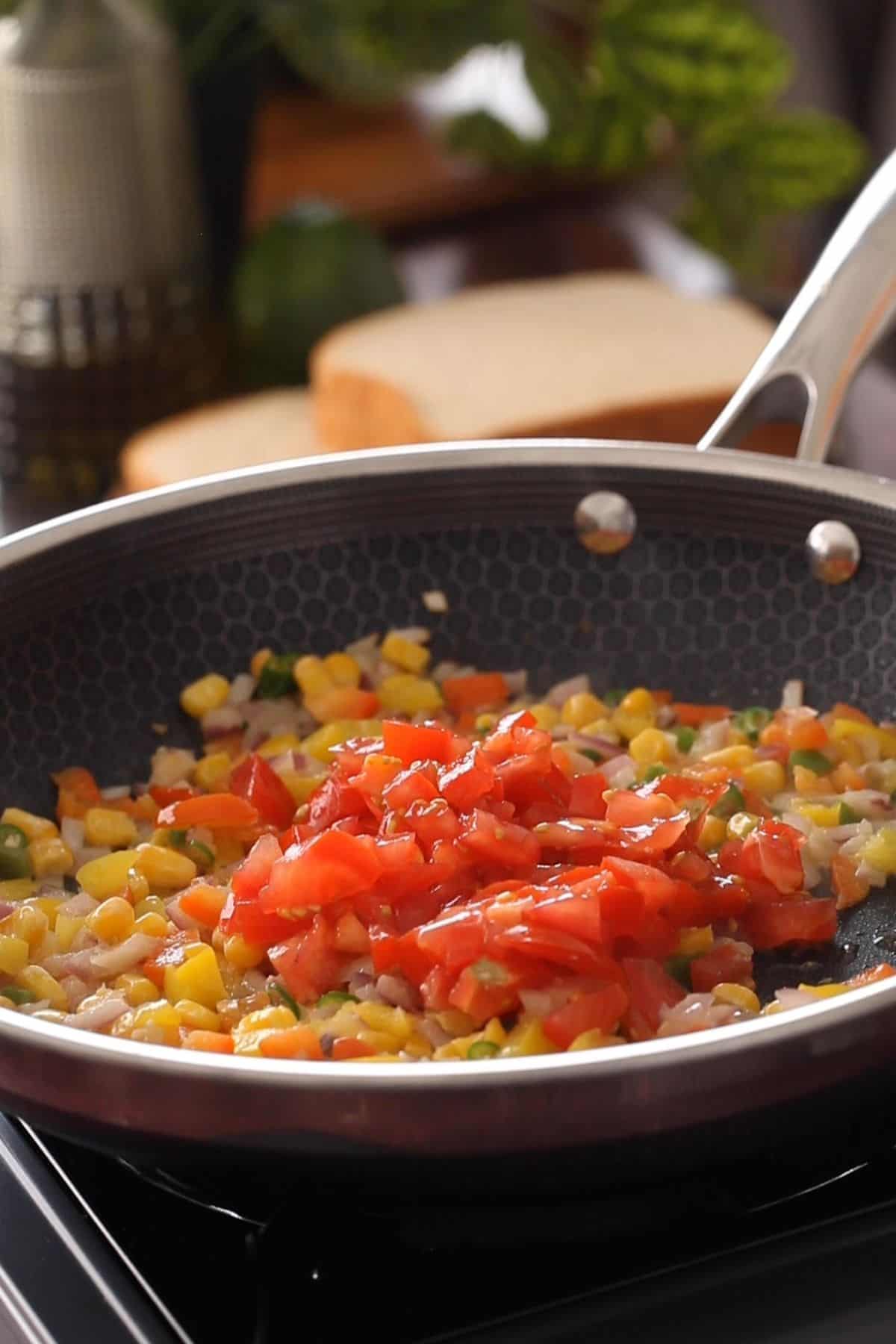Chopped tomatoes are added to the vegetables.