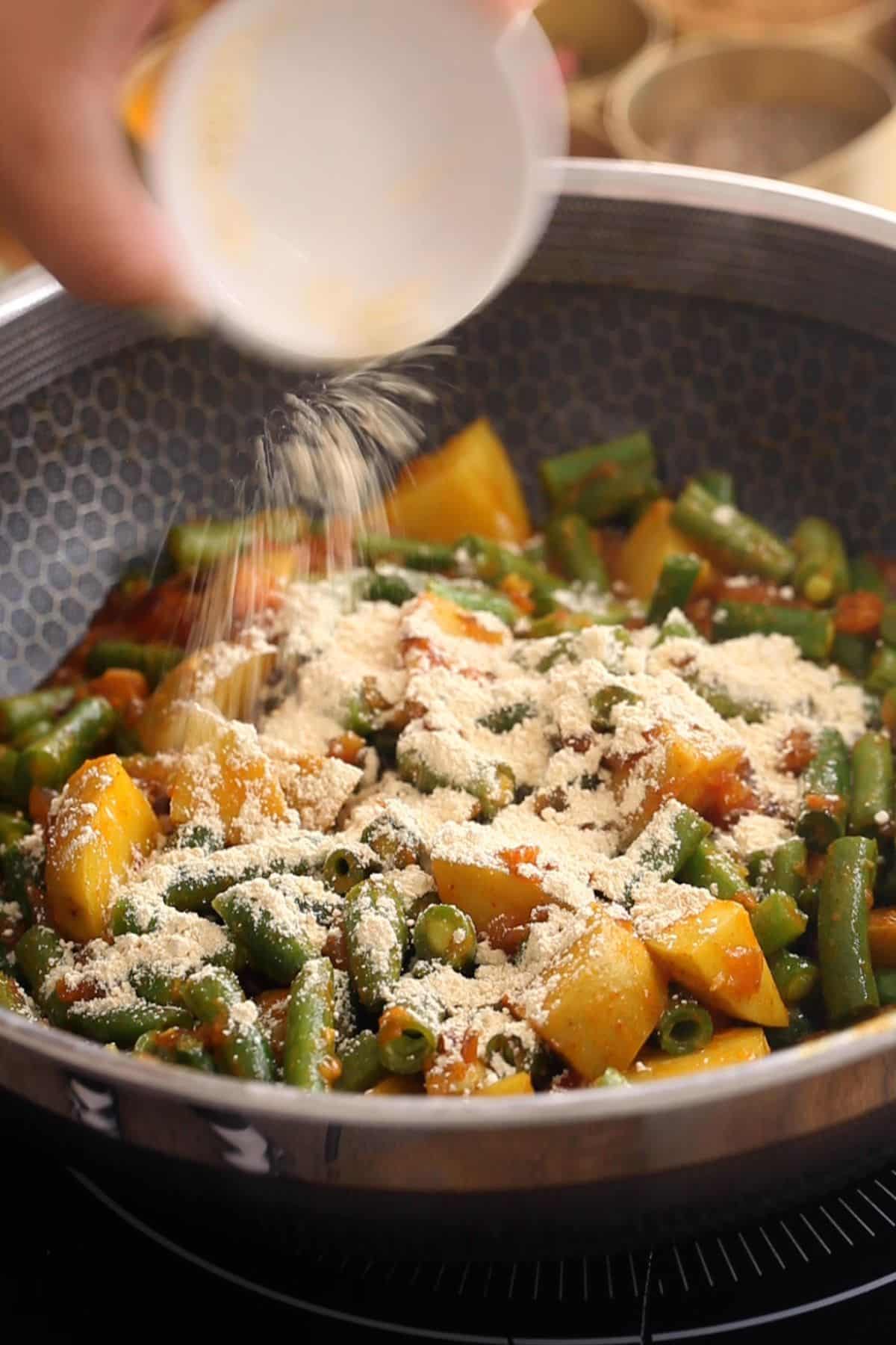 Green beasn and roasted gram flour added to the cooking pot.
