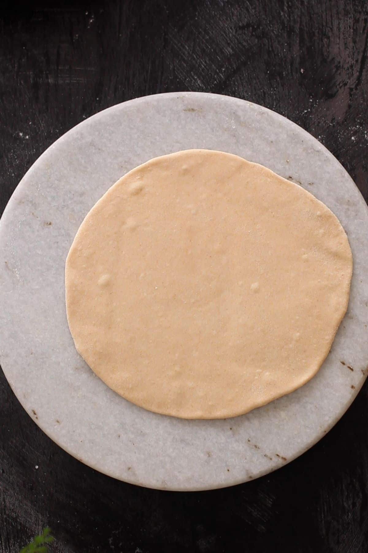 Rolled dough on a round marble board.