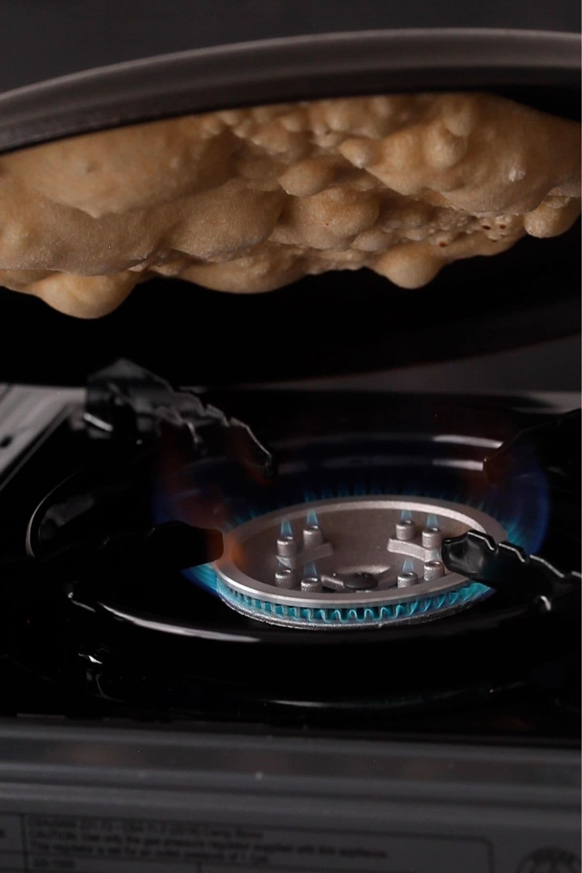 Cast iron griddle flipped over direct flame to cook tandoori roti.