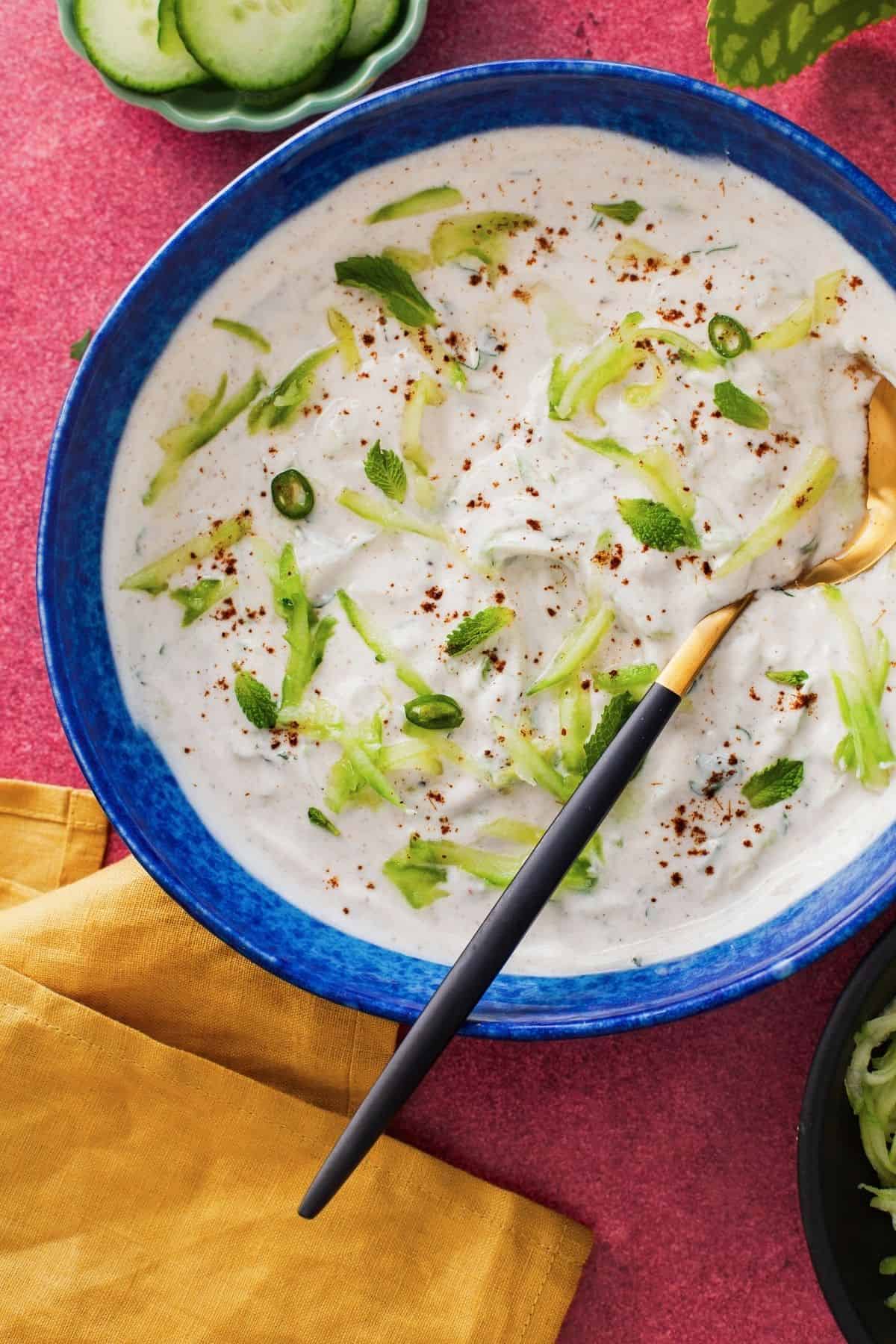 Cucumber raita served in a blue bowl.