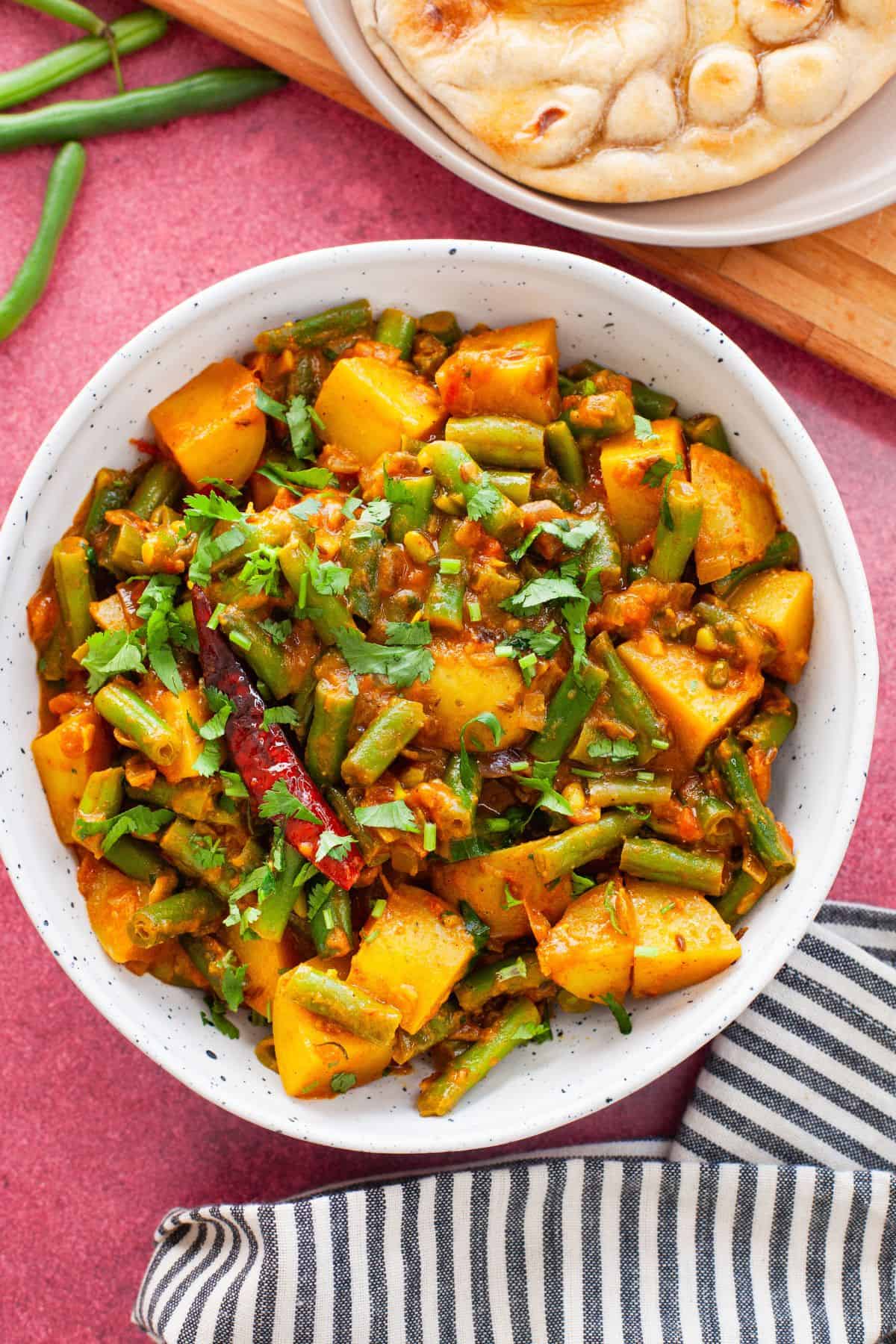 Indian green beans aloo sabji served in a white bowl.