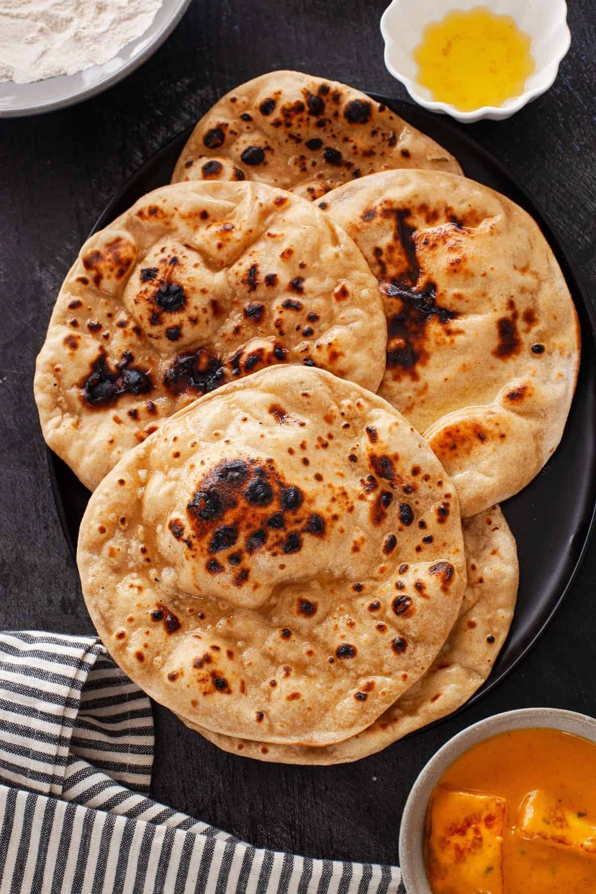 Tandoori roti in a black platter served with paneer korma.