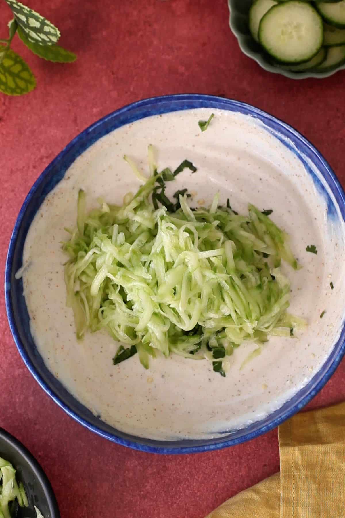 Grated cucumber, herbs and green chili is added to the spiced yogurt.