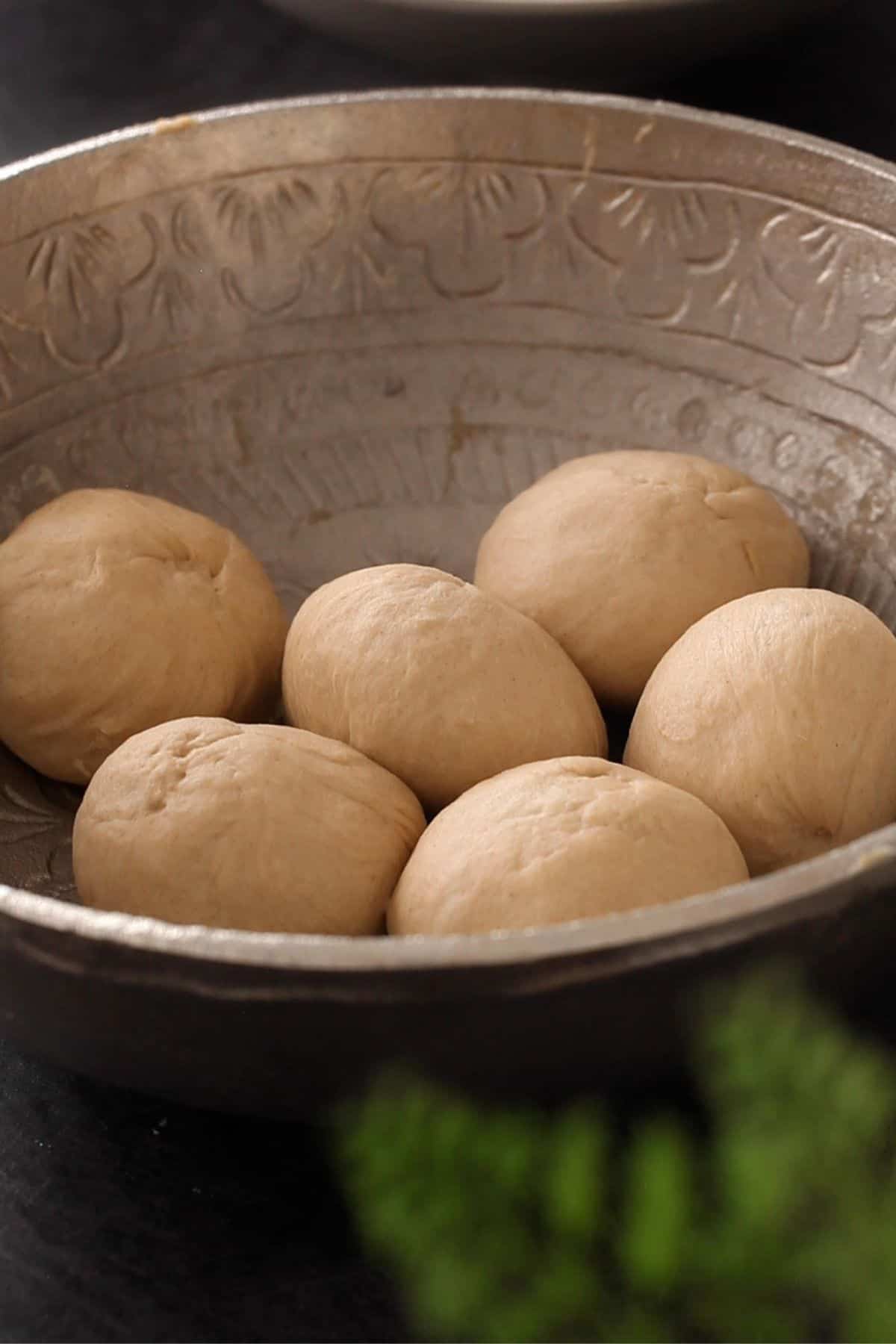 Dough balls in a silver bowl.